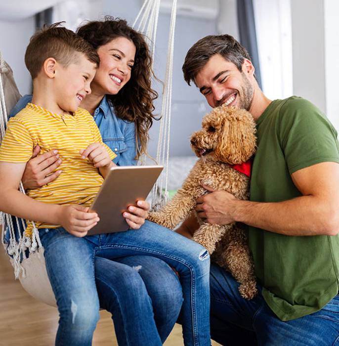 Happy young family with modern devices and dog having fun, playing at home